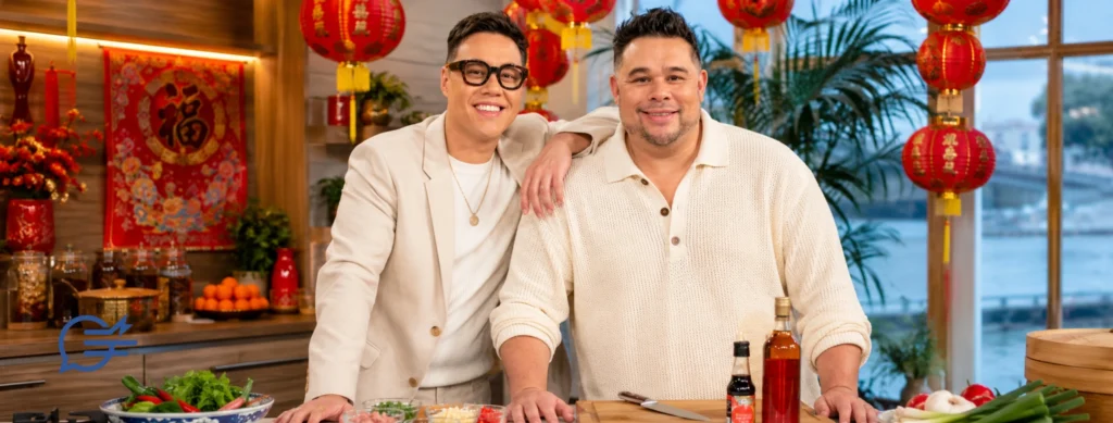 TV presenter Gok Wan and his brother chef Kwoklyn Wan smiling in a kitchen decorated with red lanterns for Chinese New Year.